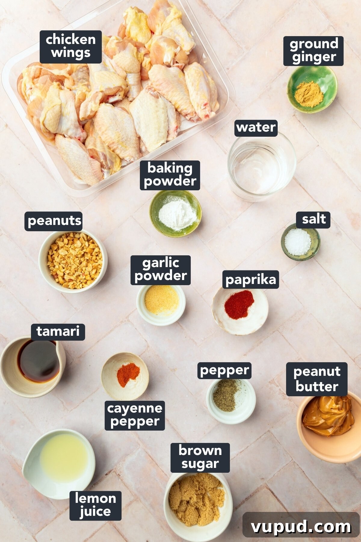 Savory Peanut Butter Glazed Chicken Wings Recipe 3 Ingredients in small bowls to make peanut butter chicken wings, including chicken wings, ground ginger, water, baking powder, peanuts, garlic powder, paprika, tamari, cayenne pepper, pepper, peanut butter, brown sugar and lemon juice.