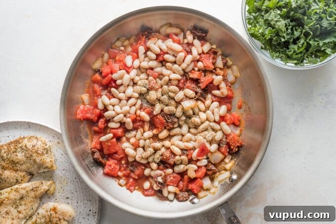 Tuscan Chicken with White Beans and Kale Recipe 5 Cannellini beans and diced tomatoes with seasoning in a skillet.