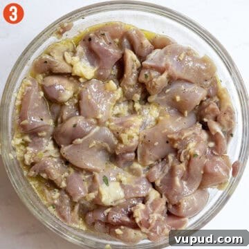 Crispy Chicken Spiedini Skewers with Lemon Herb Marinade 6 Marinating chopped chicken thighs in a bowl.