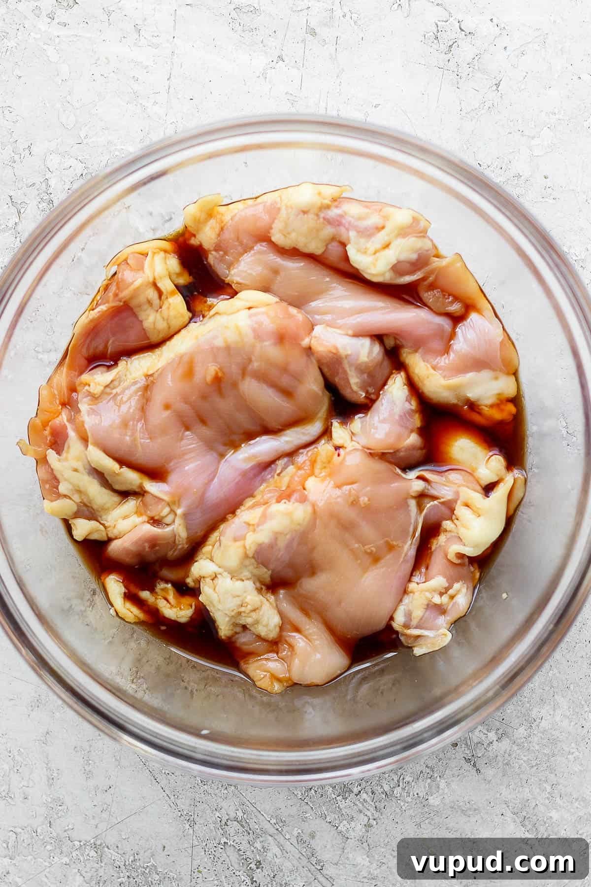 Sticky Grilled Teriyaki Chicken Recipe with Charred Scallions 3 Chicken thighs marinating in a large glass bowl with soy sauce.