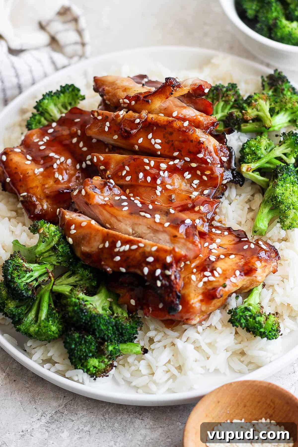 Sticky Grilled Teriyaki Chicken Recipe with Charred Scallions 5 Grilled teriyaki chicken thighs on a plate with white rice and grilled broccoli.