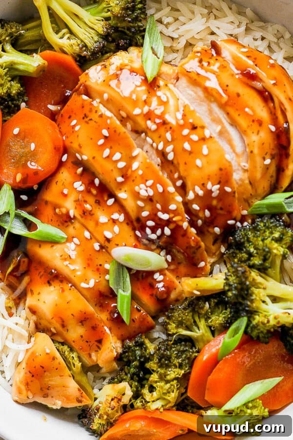 Sticky Grilled Teriyaki Chicken Recipe with Charred Scallions 7 Top down shot of a bowl of rice with baked teriyaki chicken and veggies on top with sesame seed garnish.