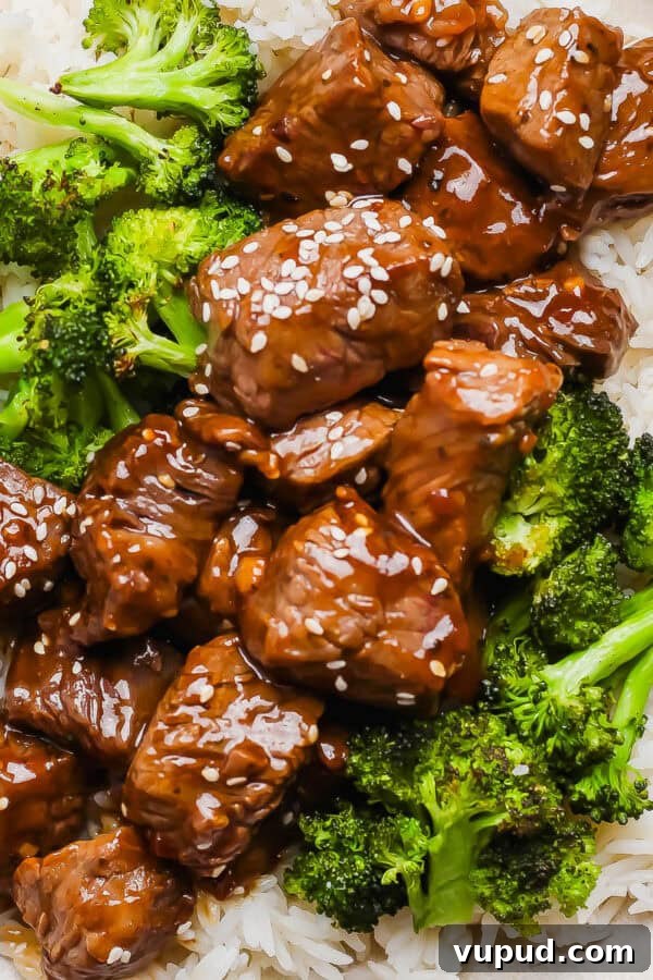 Sticky Grilled Teriyaki Chicken Recipe with Charred Scallions 8 A plate of rice with roasted broccoli and teriyaki steak bites on top with sesame seeds.