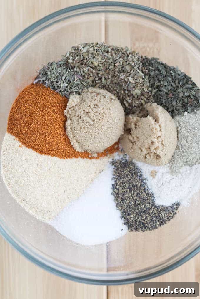 Homemade Cajun Seasoning Blend for Authentic Louisiana Flavor 3 large glass mixing bowl full of spices but not combined, so they are all sitting separated into piles next to each other in a circular pattern sitting on a wooden table