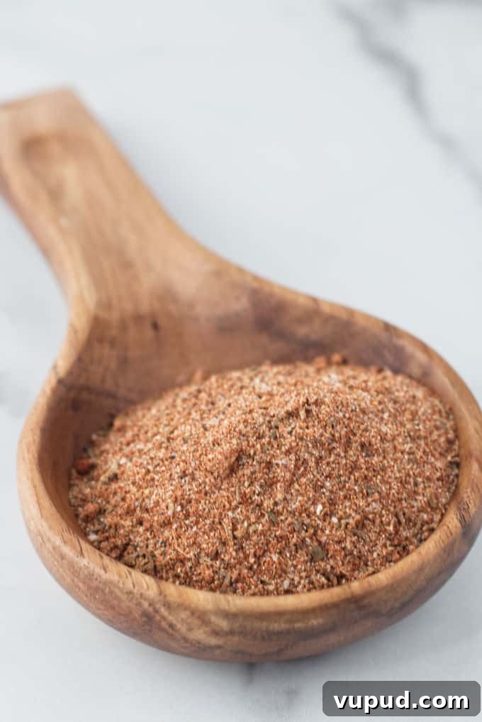 Homemade Cajun Seasoning Blend for Authentic Louisiana Flavor 4 Large wooden spoon filled with brownish red cajun spice seasoning sitting on a marble table