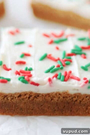 Frosted gingerbread cookie bars cut into squares on parchment paper.