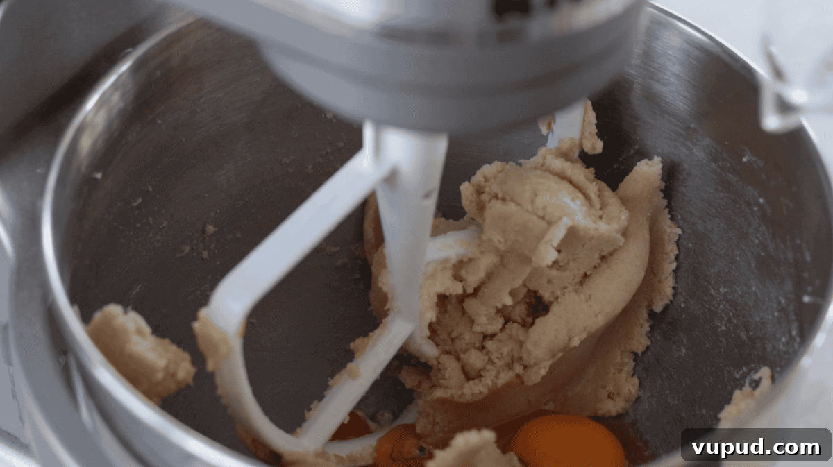 Classic Chewy Toffee Bars Recipe with Buttery Shortbread 5 Stand mixer mixing eggs into cookie dough.
