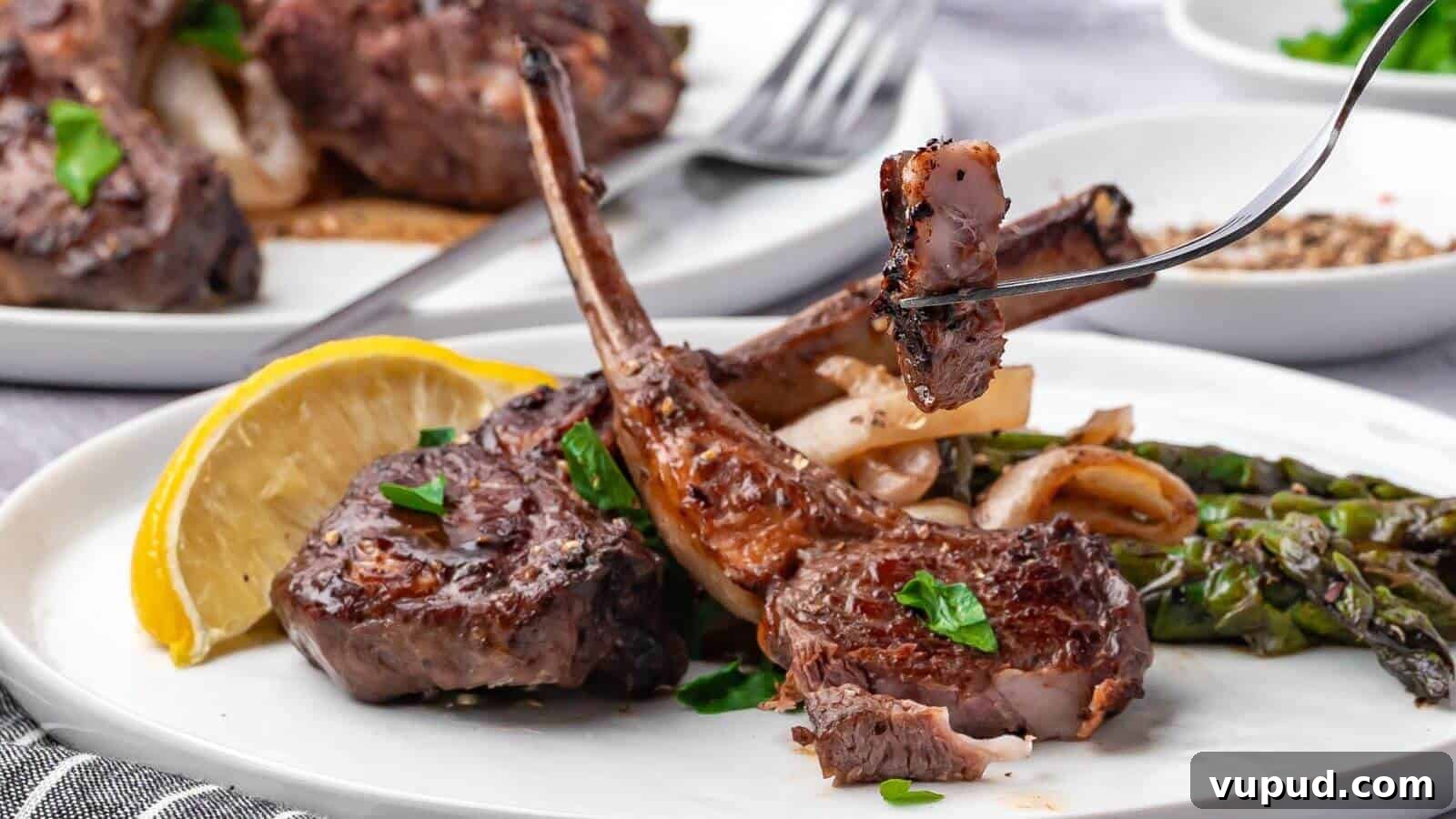 30 Flavorful Low-Carb Main Dishes That Feel Like Real Meals 2 Grilled lamb chops with herbs on a plate, alongside asparagus, onions, and a lemon wedge. A fork holds a piece of meat above the plate.