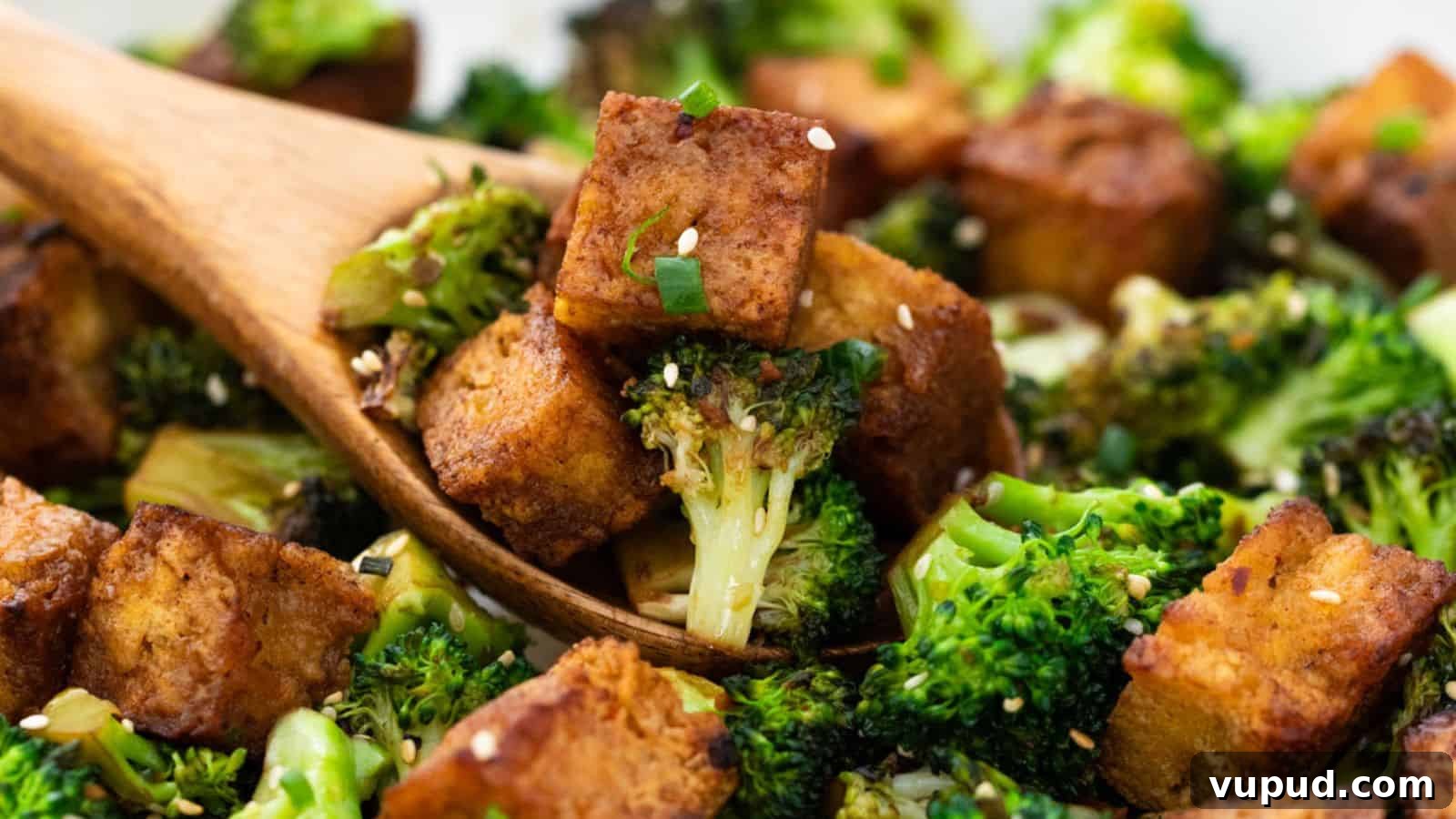 30 Flavorful Low-Carb Main Dishes That Feel Like Real Meals 29 Roasted broccoli and tofu cubes garnished with sesame seeds and green onions, served with a wooden spoon.