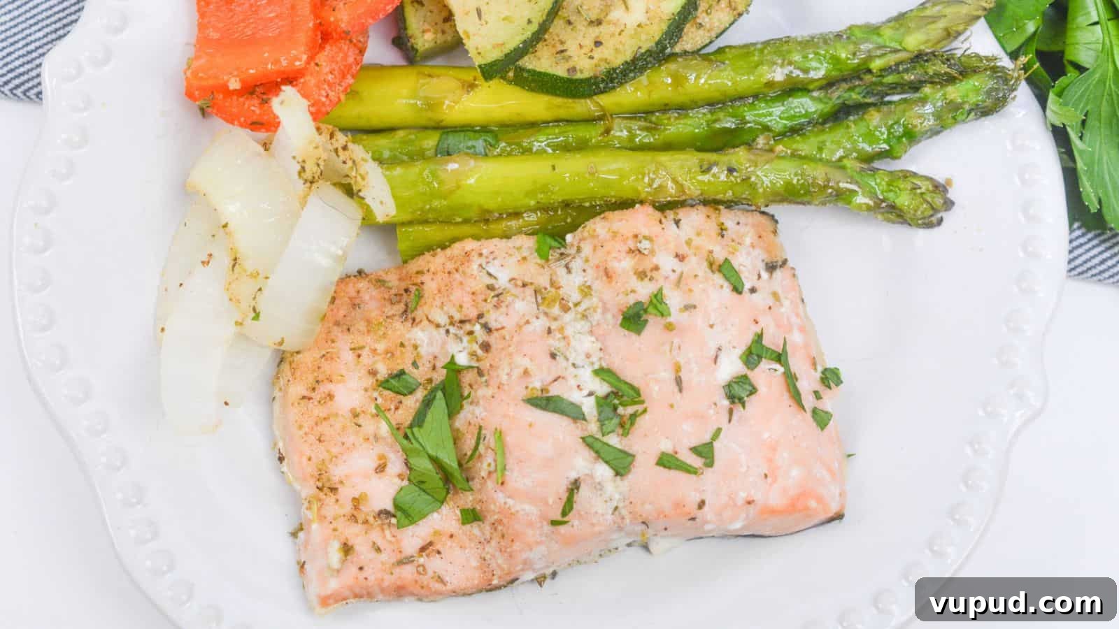 30 Flavorful Low-Carb Main Dishes That Feel Like Real Meals 31 Baked salmon fillet with asparagus, zucchini, and bell peppers on a white plate, garnished with herbs.