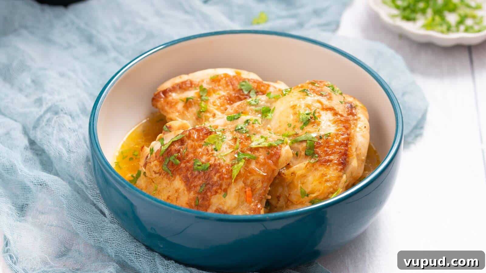 30 Flavorful Low-Carb Main Dishes That Feel Like Real Meals 5 A blue bowl of cooked chicken breasts garnished with chopped herbs on a light fabric backdrop.