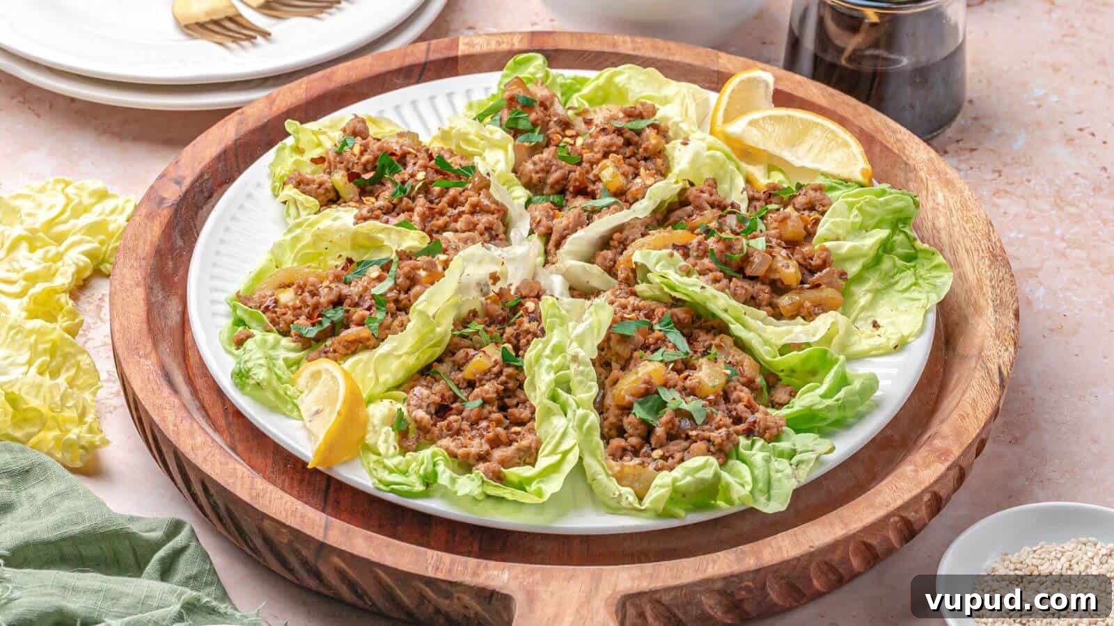 30 Flavorful Low-Carb Main Dishes That Feel Like Real Meals 10 A plate of lettuce wraps filled with seasoned minced meat and garnished with herbs, served with lemon wedges on a wooden tray.