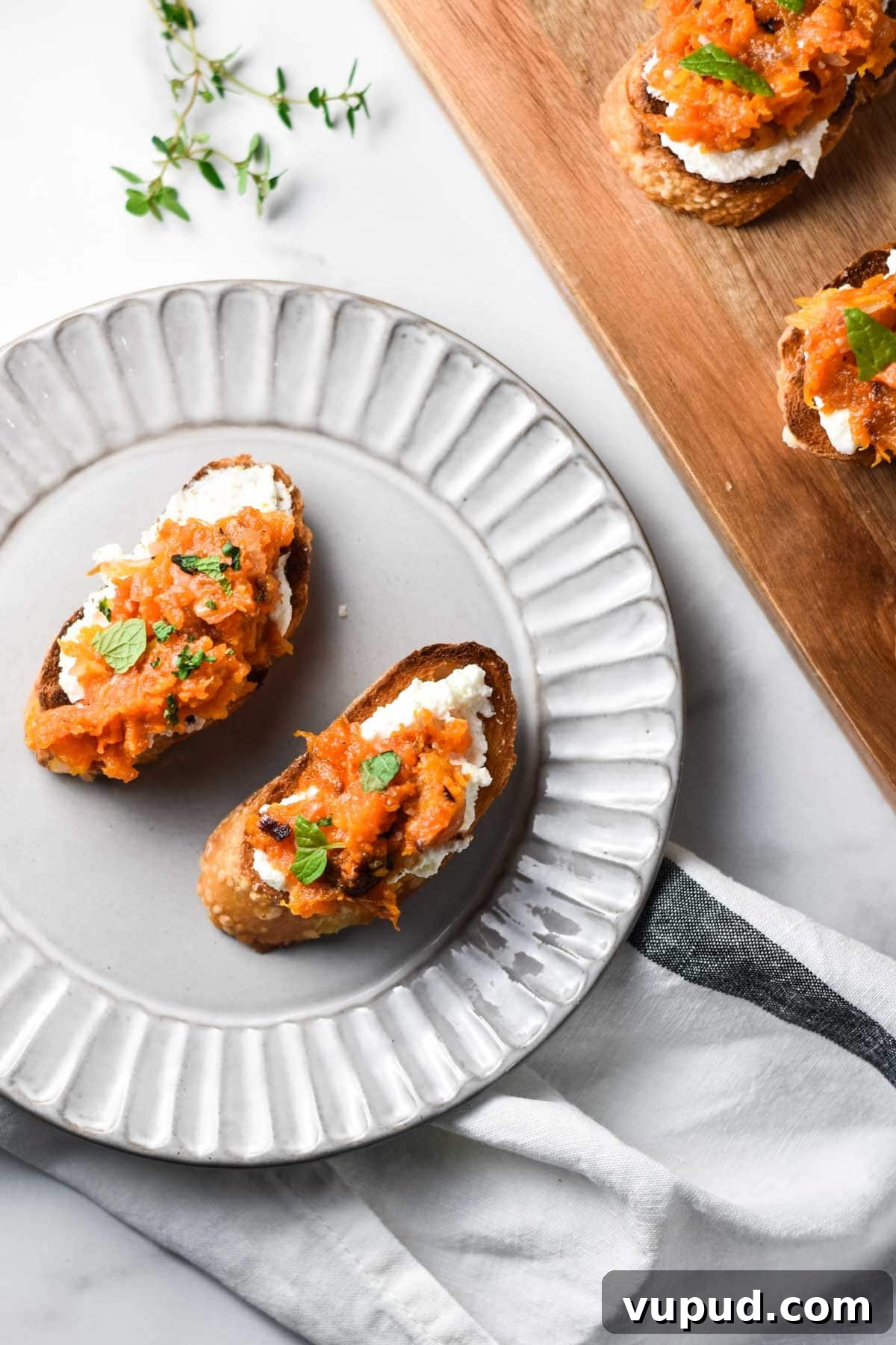 Butternut Squash Crostini with Goat Cheese and Sage 2 A plate of butternut squash appetizers next to a cutting board with crostini.