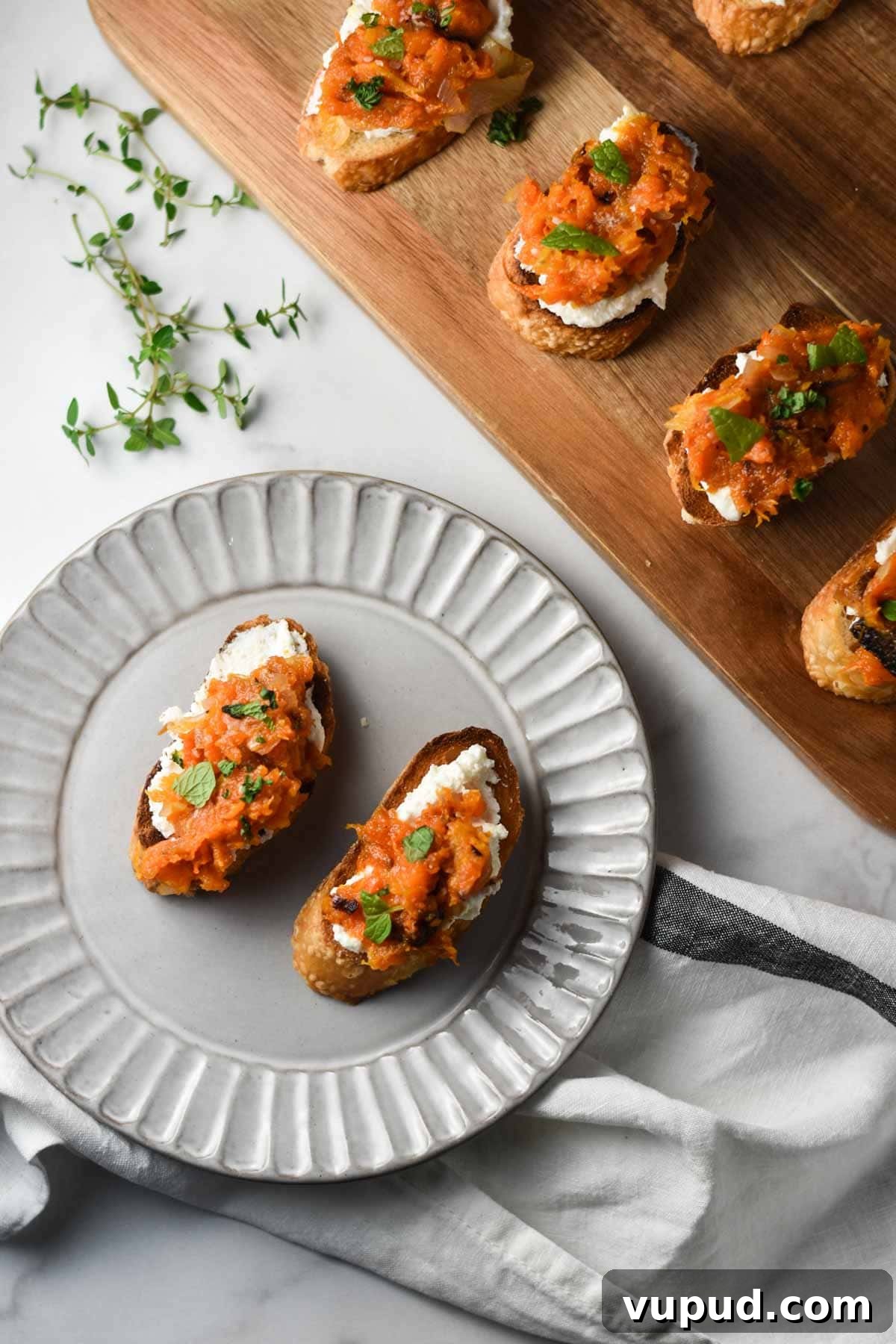 Butternut Squash Crostini with Goat Cheese and Sage 8 Two crostini topped with butternut squash on a grey plate.