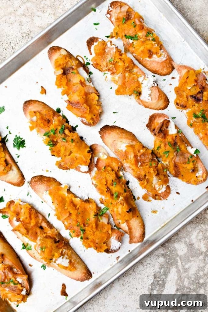 Butternut Squash Crostini with Goat Cheese and Sage 10 Butternut squash crostini lined up on a sheet pan and sprinkled with mint.