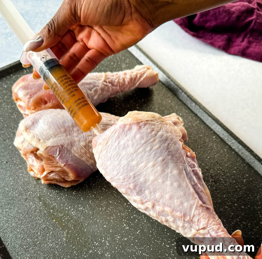 Smoky Traeger Turkey Legs Recipe: Juicy Wood-Fired Flavor 6 person injecting raw turkey leg with butter