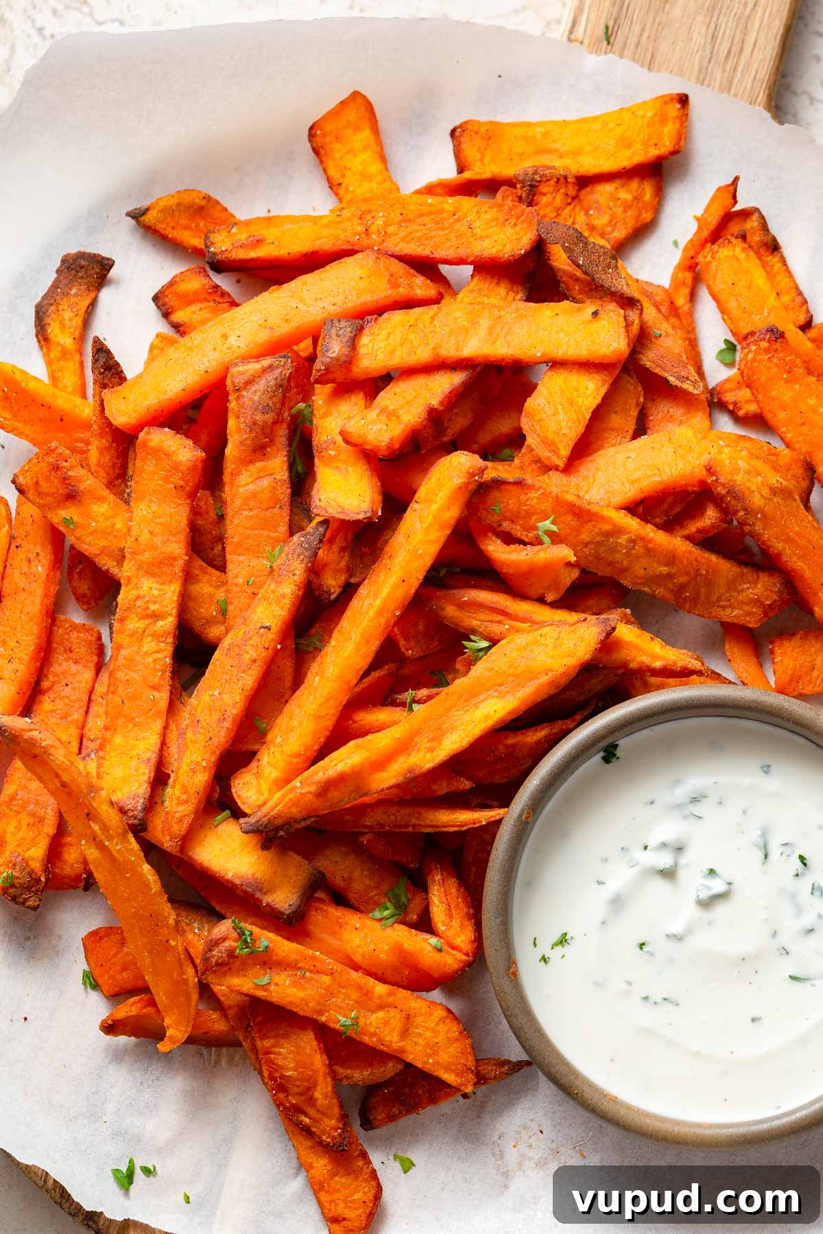 Crispy Air Fryer Frozen Sweet Potato Fries in Minutes 8 frozen sweet potato fries in the air fryer with a dip on the side.