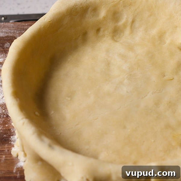 How to Blind-Bake a Pie Crust for a Perfect Fill 6 Pie crust dough fitted into a pie plate before the edges are trimmed.