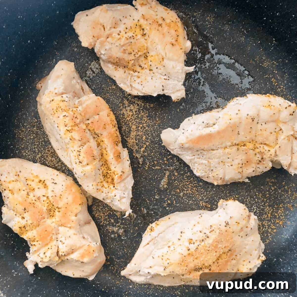 Seared chicken breasts in a large skillet.