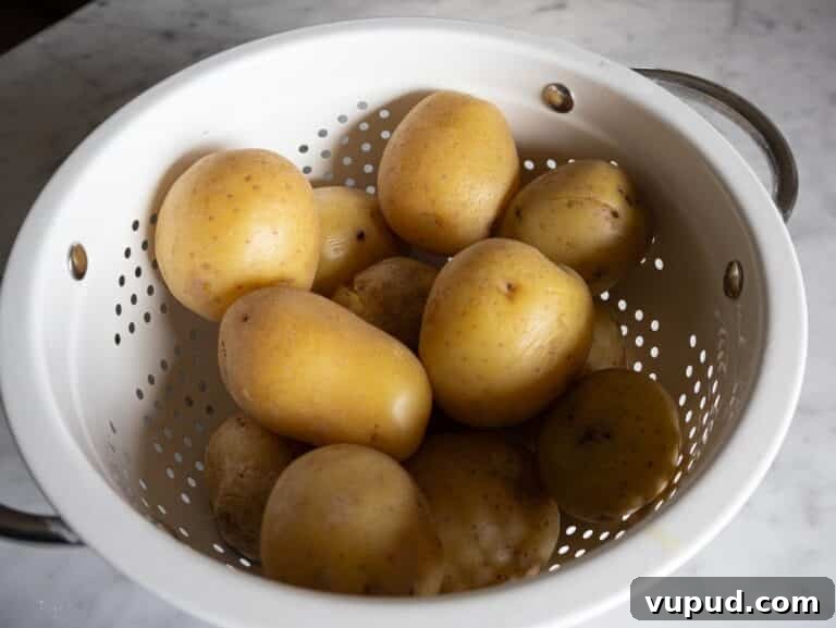 Creamy Garlic Mashed Potatoes Recipe 11 Boiled potatoes steaming off in a colander.