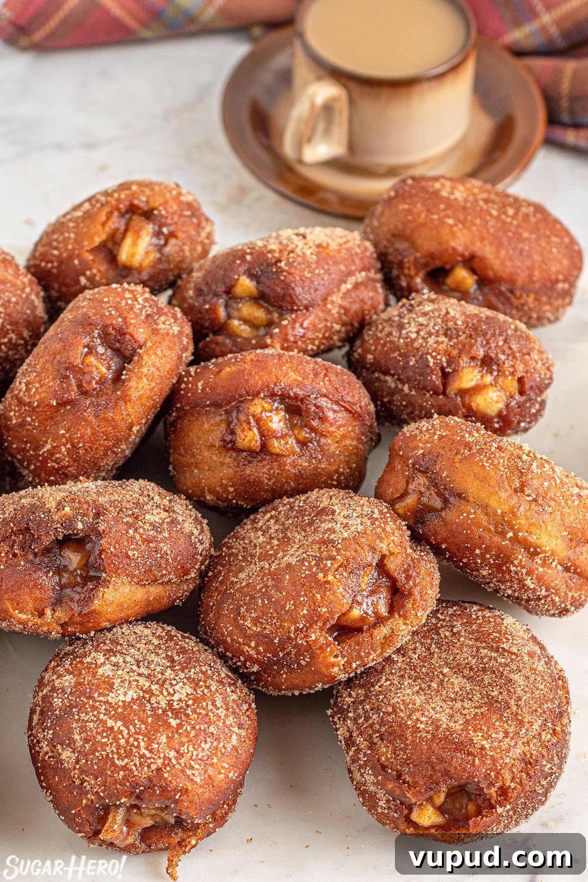 Caramel Apple Donut Recipe: Homemade Baked Apple Donuts with Streusel 10 A group of Apple Donuts on a marble surface with a cup of coffee in the background.