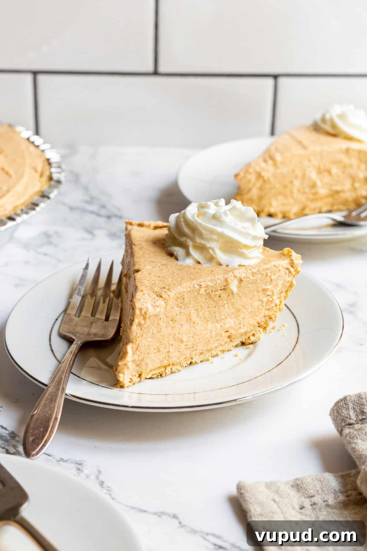 No-Bake Pumpkin Cheesecake with Gingersnap Crust 2 slice of no bake pumpkin cheesecake served on a round plate with a silver fork