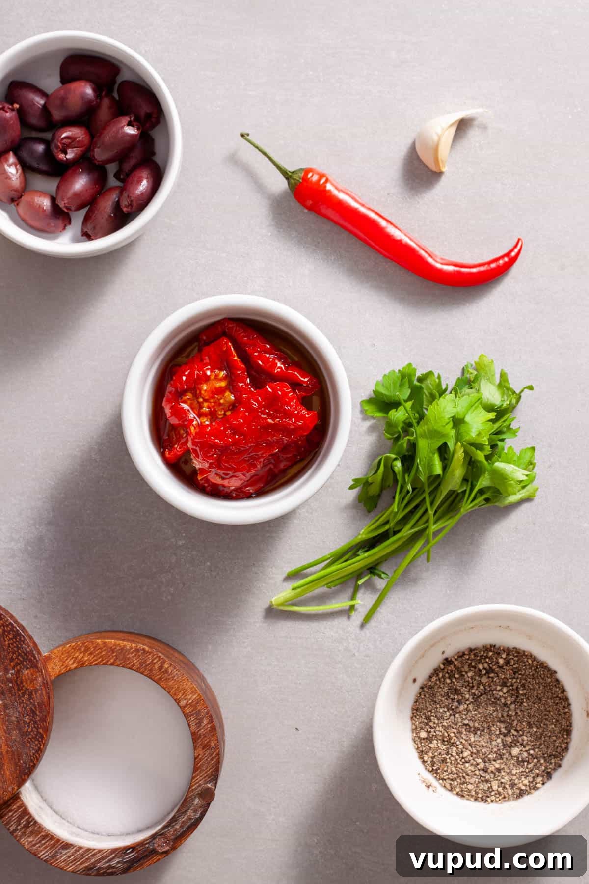 Ingredients for homemade sun-dried tomato spread on a gray table.
