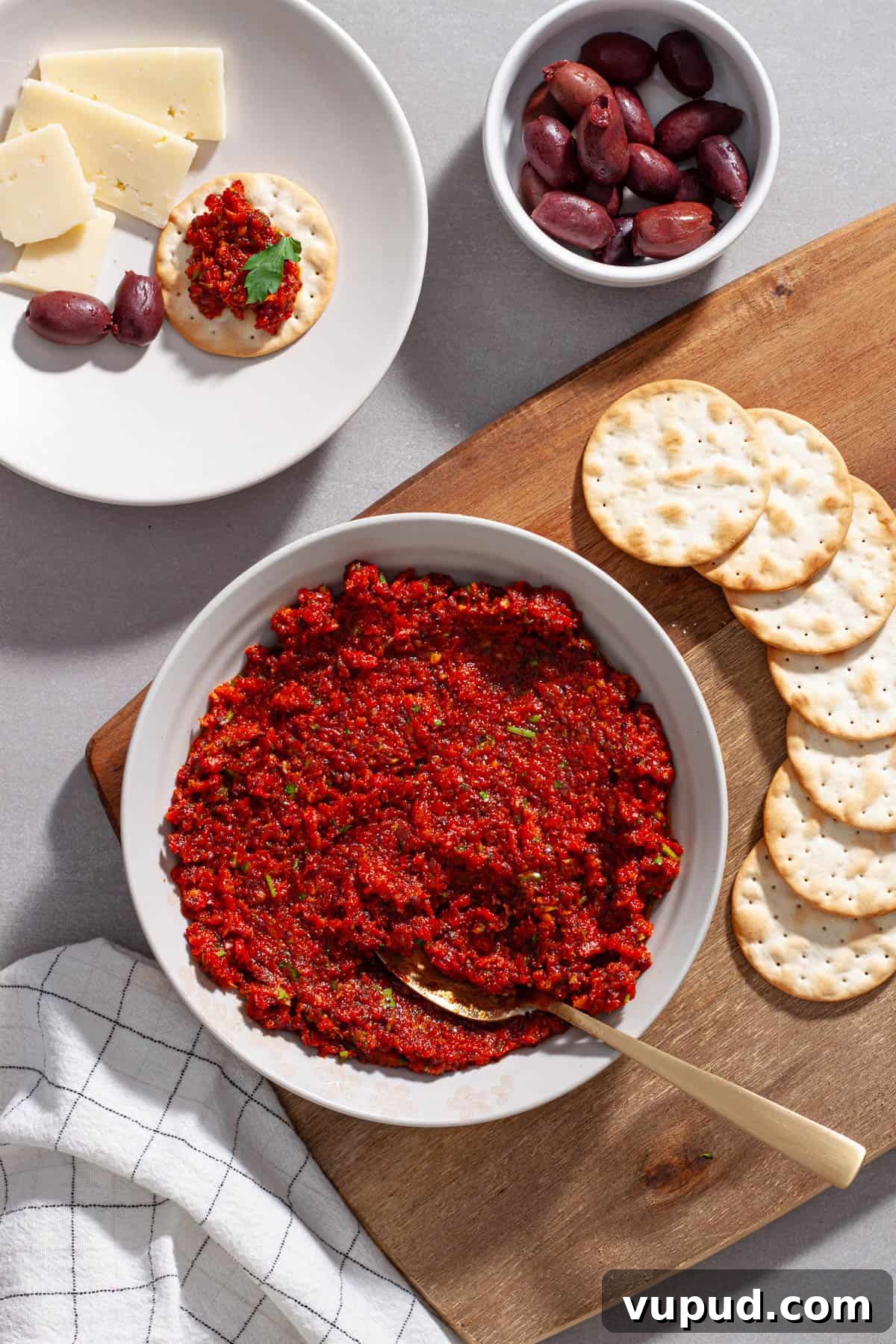 A cheese board with sun-dried tomato spread on a cutting board.