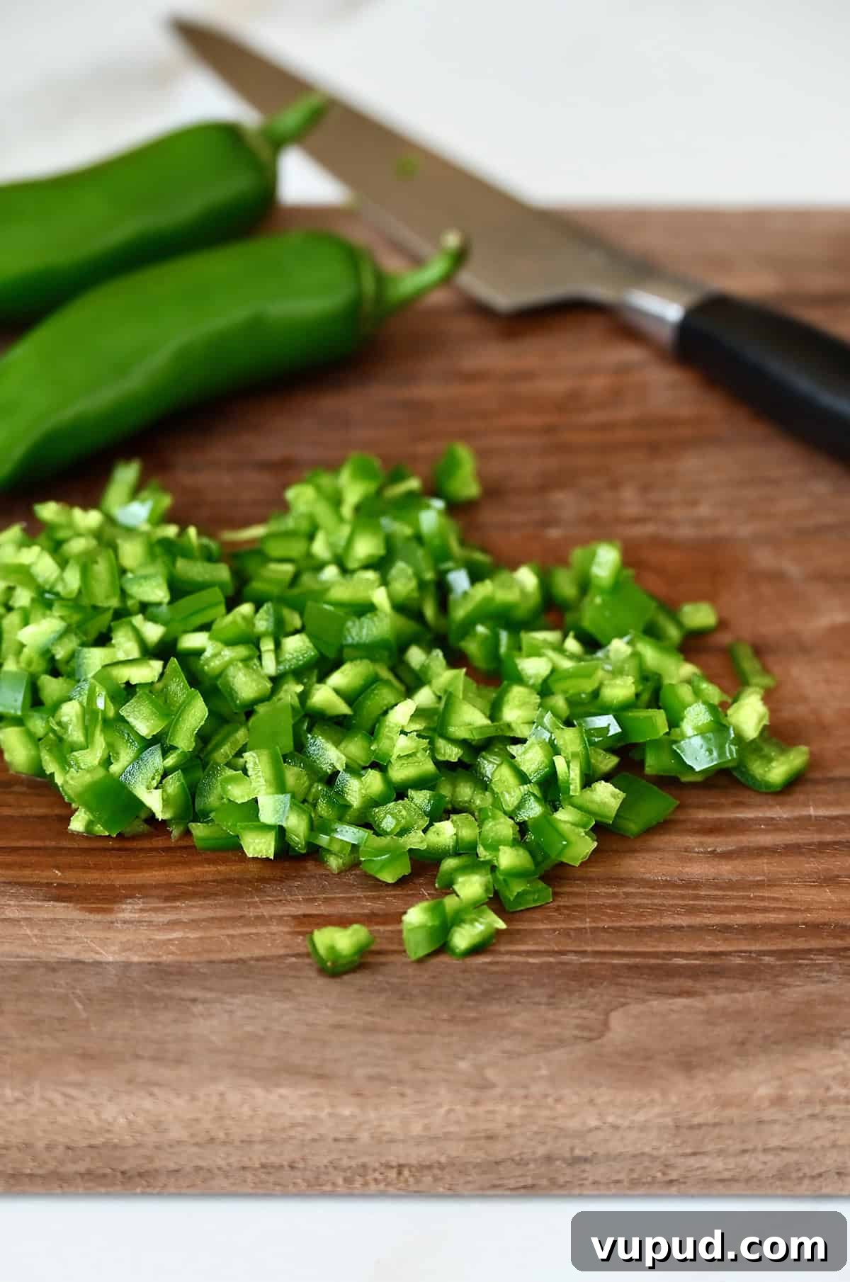 Creamy Jalapeño Popper Dip Recipe for Parties and Game Day 5 Diced jalapeños on a wood cutting board.