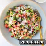 Broccoli salad in a bowl with a fork and extra tahini dressing in a little dish.