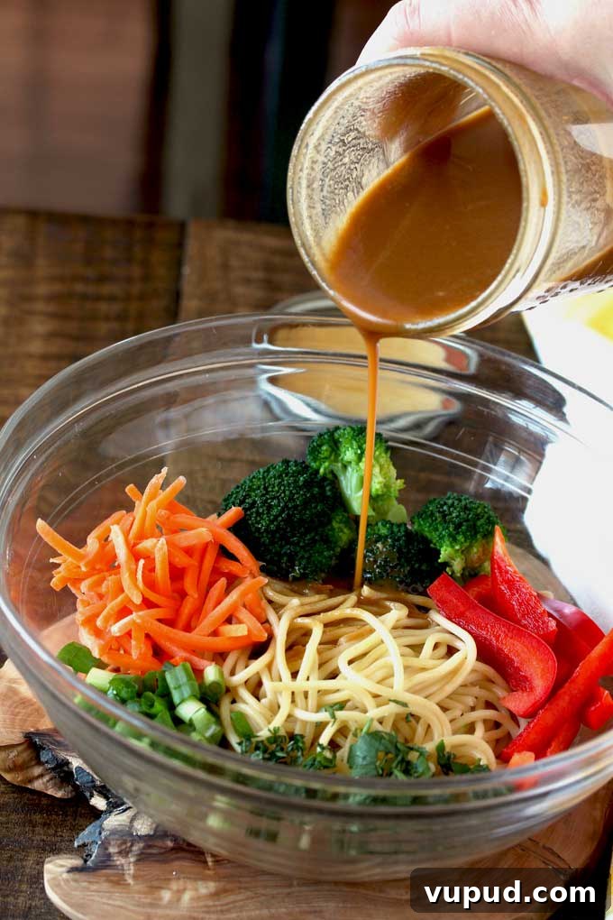 $80 Weekly Meal Plan: 5 Budget-Friendly Dinners for the Week 9 Peanut Sesame Dressing poured over noodles and vegetables.