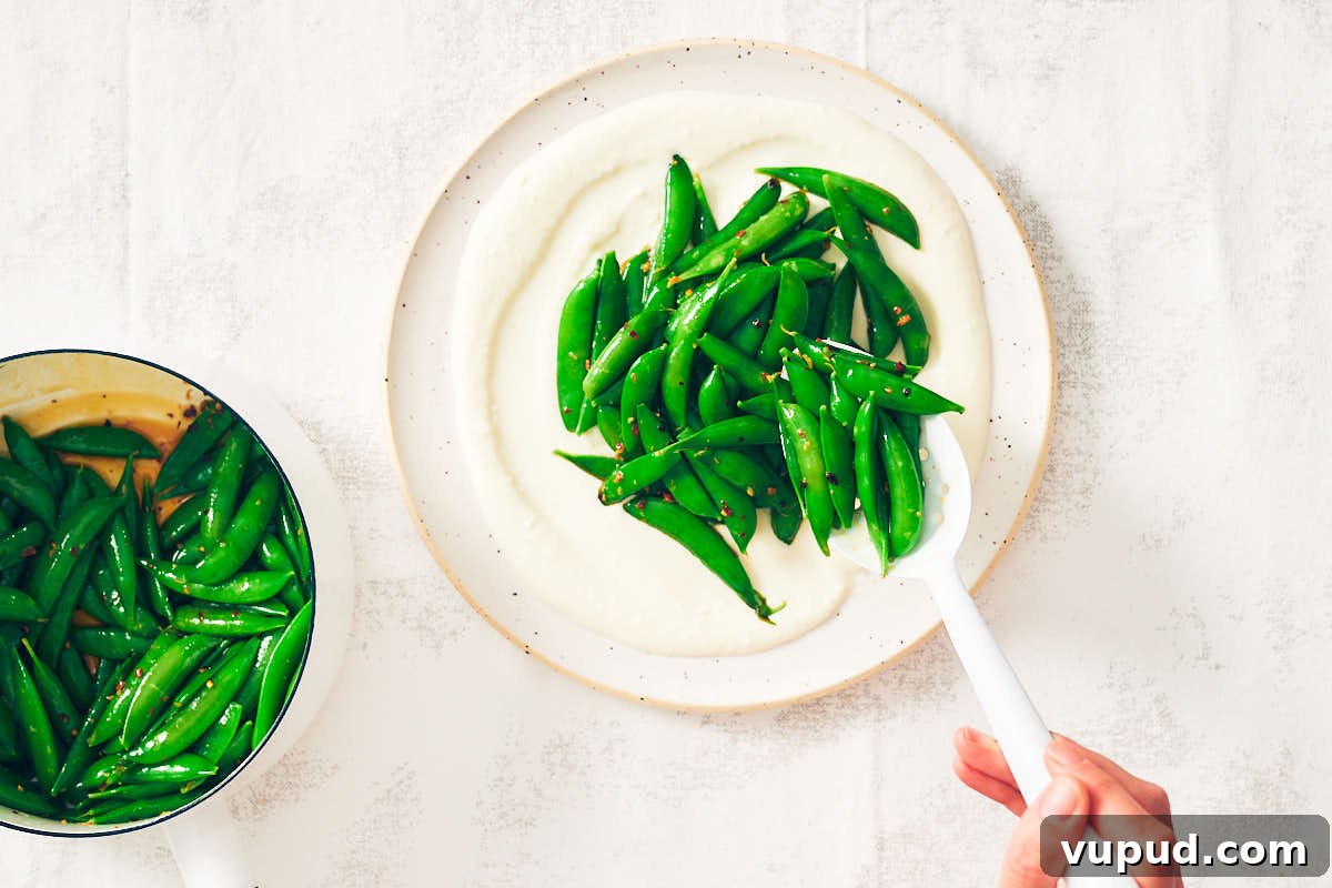 Crisp Snap Pea Salad with Whipped Feta and Lemon Vinaigrette 12 Spooning Snap Pea Salad over whipped feta on a plate.