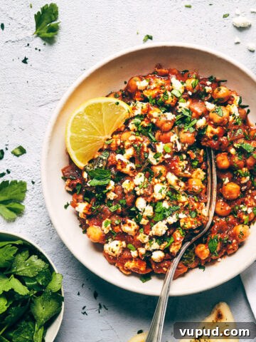 Close up of Mediterranean chickpea casserole topped with parsley, feta and lemon