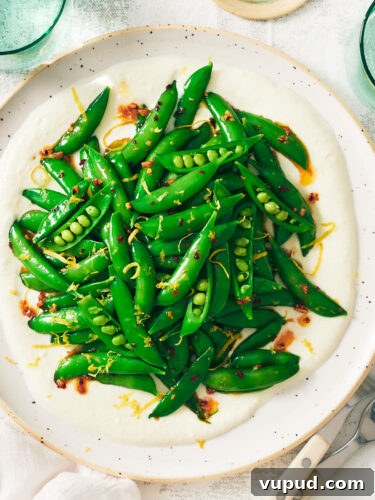 Crisp Snap Pea Salad with Whipped Feta and Lemon Vinaigrette 18 A plate of Snap Pea Salad on whipped feta on a table.