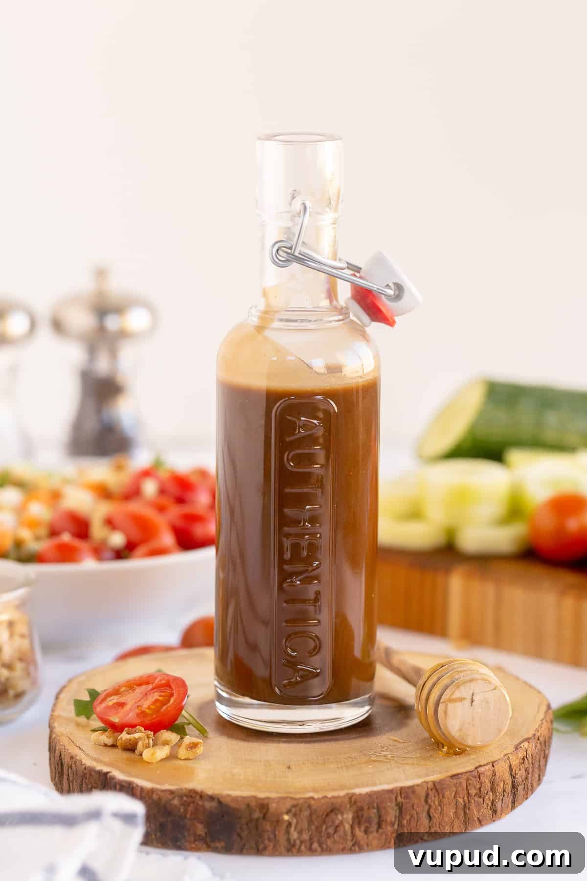Honey Balsamic Vinaigrette Recipe for Salads and Marinades 3 A glass container filled with salad dressing with vegetables around it.