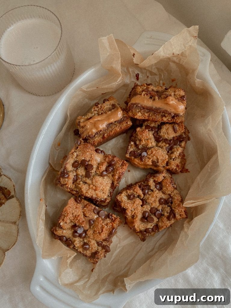 Peanut Butter Chocolate Layer Bars (Grain-Free Recipe) 4 Grain Free Peanut Butter Chocolate Cookie Layer Bars on parchment paper in a white baking dish