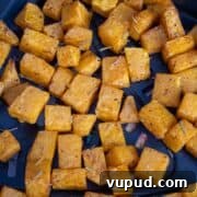 Crispy Air Fryer Butternut Squash Recipe: Quick Roasted Cubes 12 Cubed squash at the bottom of an air fryer basket cooked.