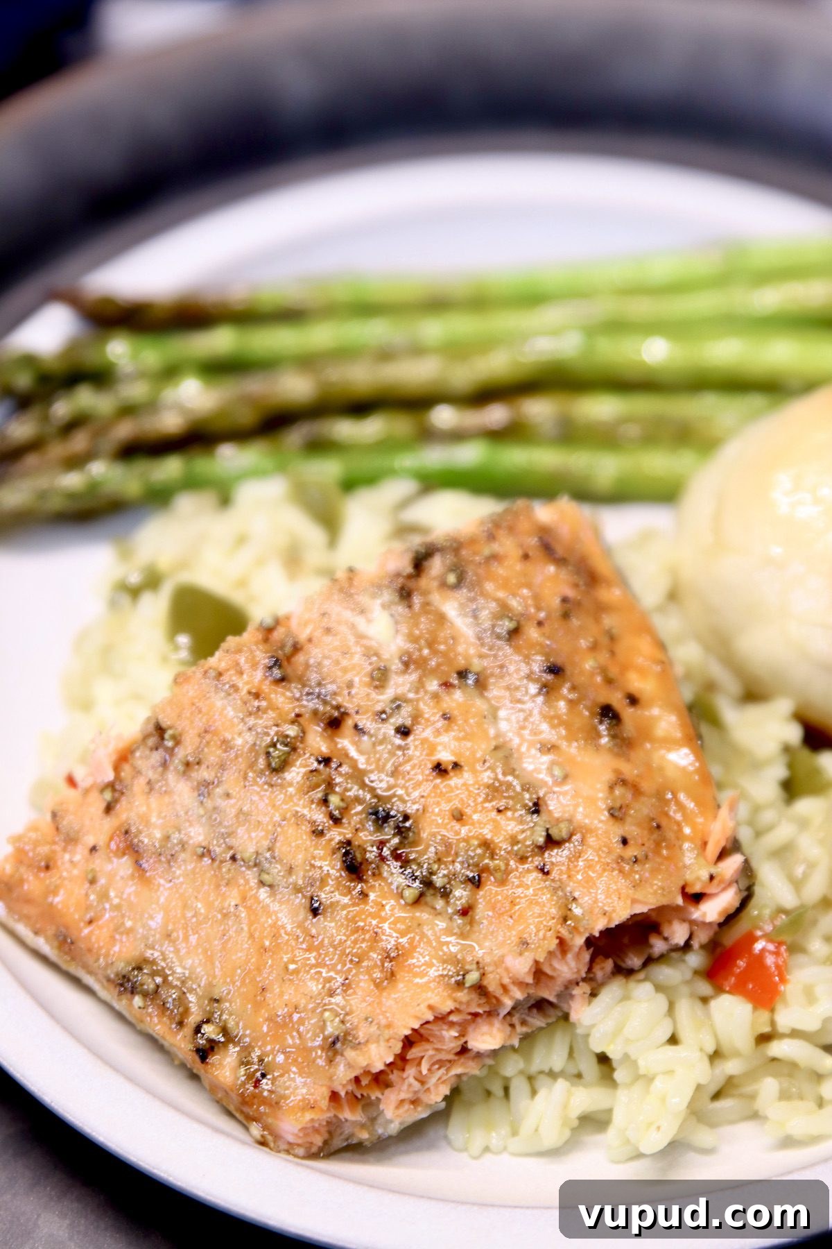 Grilled Maple Glazed Salmon Grilled Salmon filet over rice, asparagus, and roll on the plate.
