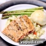 Maple-Glazed Salmon Recipe with Crispy Skin and Bold Flavor 2 Salmon filet on a plate with rice, asparagus & a dinner roll.