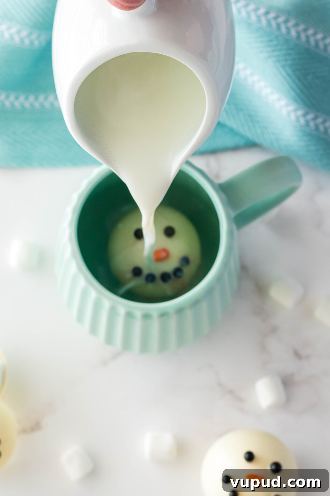 Snowman Hot Chocolate Bombs Recipe for Cozy Winter Drinks 5 hot milk being poured into a mug with a snowman hot cocoa bomb inside