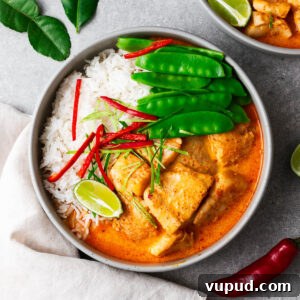 Authentic Thai Red Curry with Fish: Quick Flavorful Recipe 11 A bowl with steamed jasmine rice, Thai fish red curry and snow peas topped with sliced red chile and kaffir lime leaves.