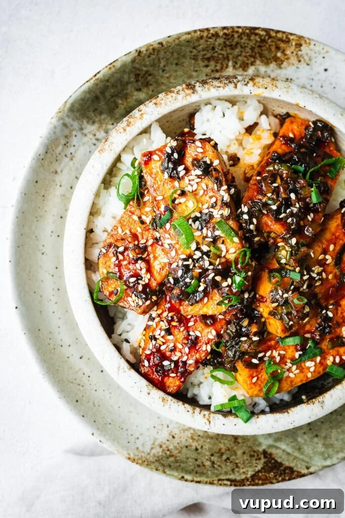 Authentic Thai Red Curry with Fish: Quick Flavorful Recipe 13 Top down close-up of a ceramic bowl with white rice topped with Korean braised tofu, sesame seeds and green onion.