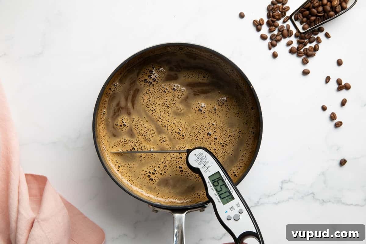 Homemade Espresso Ice Cream Recipe: Rich Coffee Gelato at Home 5 A saucepan with combined egg yolks, sugar and milk with espresso powder in it. A thermometer is in it to read the temperature.