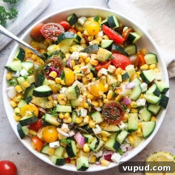 bowl with tomato corn cucumber salad tossed in lemon juice and olive oil.