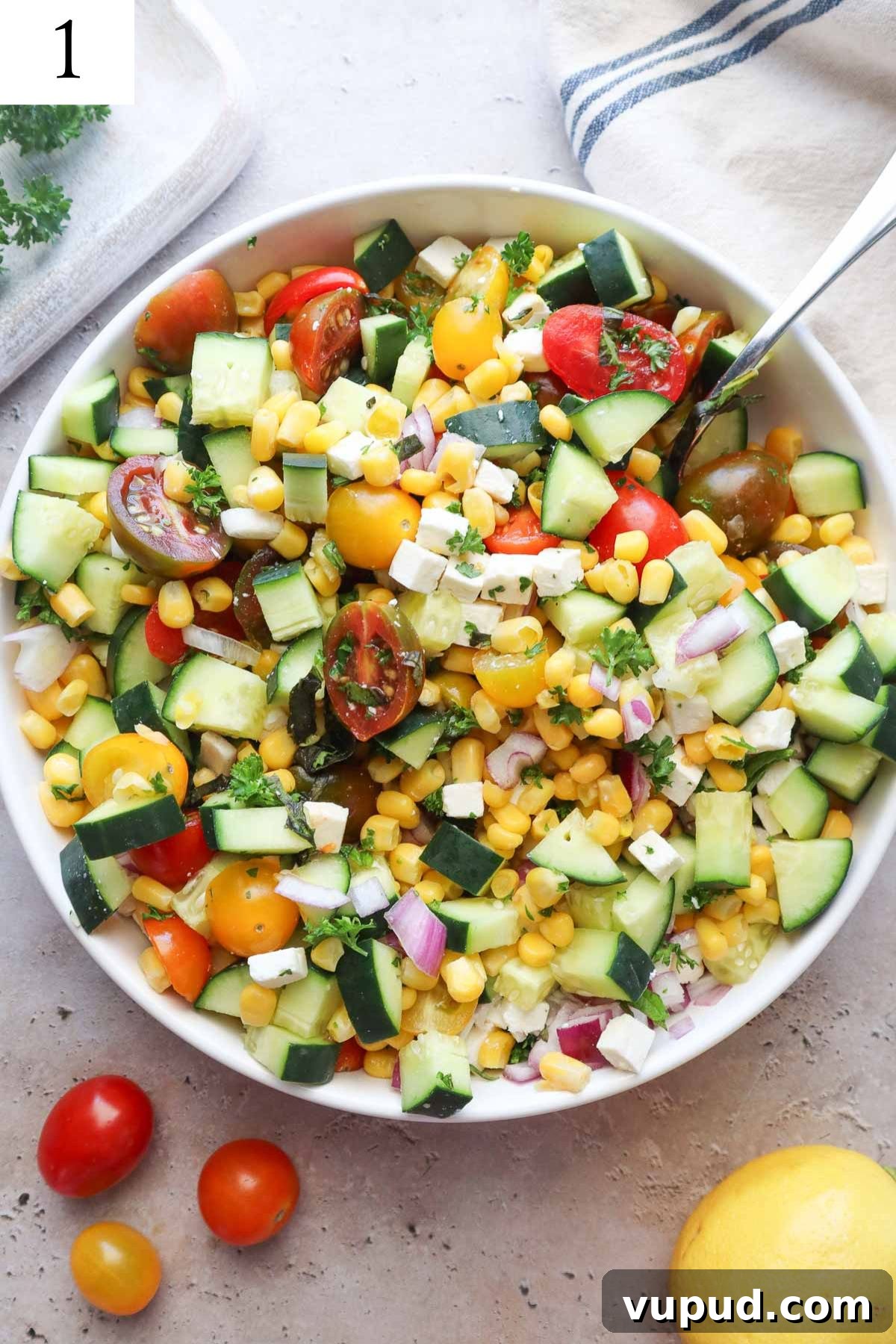 white bowl with mixed ingredients to make tomato corn cucumber salad mixed together without seasonings.