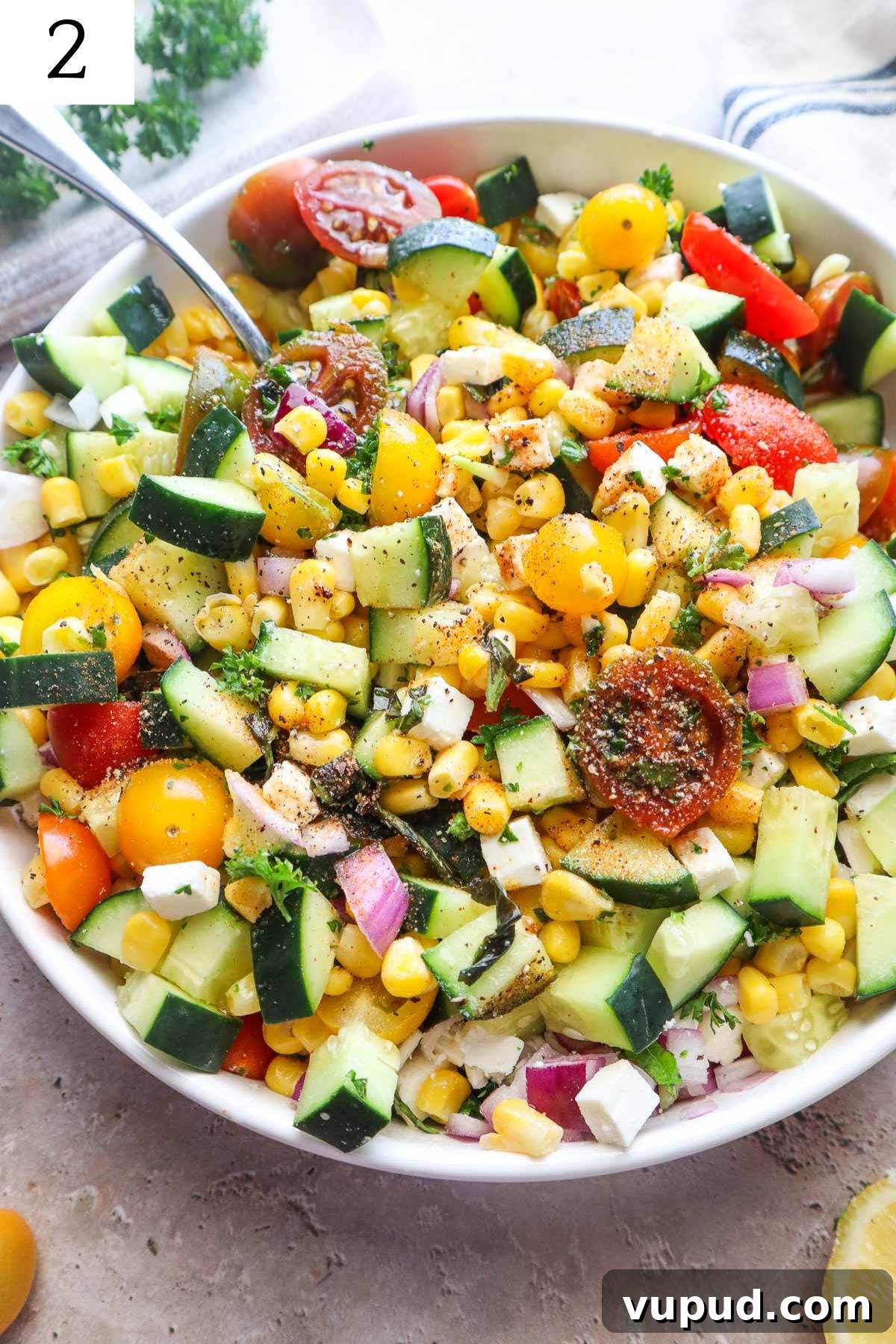 all ingredients to make tomato corn cucumber salad in a bowl all mixed together with seasonings.