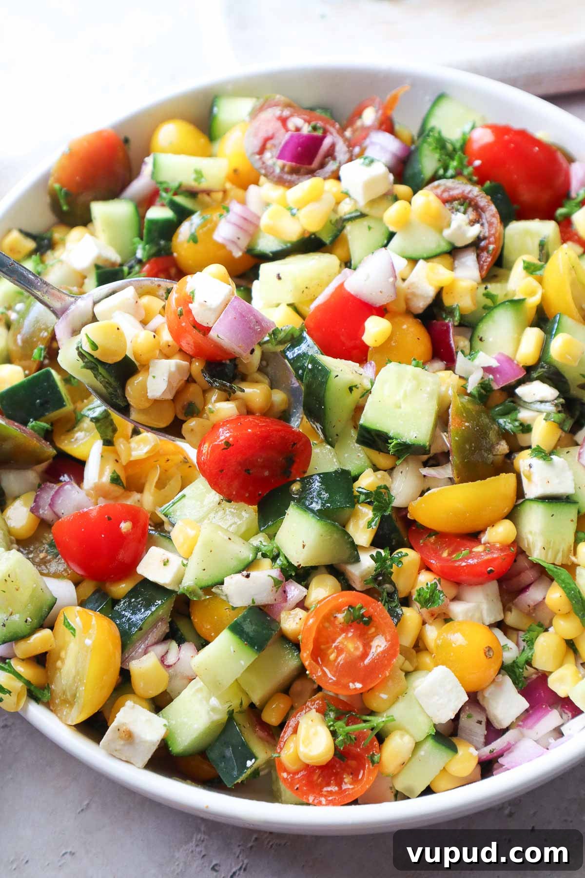 bowl with tomato corn cucumber salad tossed in lemon juice and olive oil.