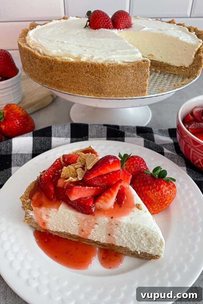 No-Bake Strawberry Cheesecake with Fresh Strawberries 2 Easy strawberry cheesecake on a serving plate topped with fresh strawberry syrup. Large cheesecake pictured in the background with a slice taken out of it.