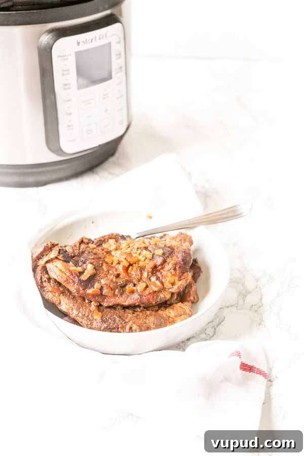 Juicy Pork Shoulder Steak in the Instant Pot: Quick Tender Recipe 6 Pork shoulder steak served on a white plate with a fork.