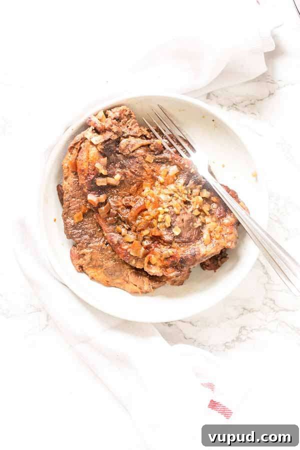 Juicy Pork Shoulder Steak in the Instant Pot: Quick Tender Recipe 7 Close up of an Instant Pot pork shoulder steak on a white plate with a fork.